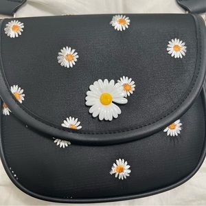 Black Daisy Crossbody. NWOT. Has interchangeable straps.